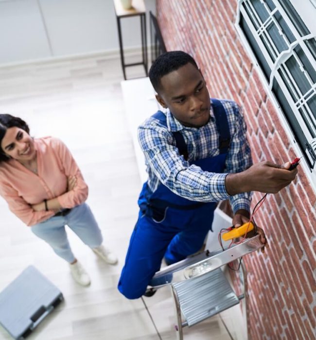 An AC technician troubleshooting a split Air conditioner- and a landlady smiling relaxed burden free